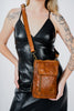 a woman wearing a black leather dress holding a brown purse