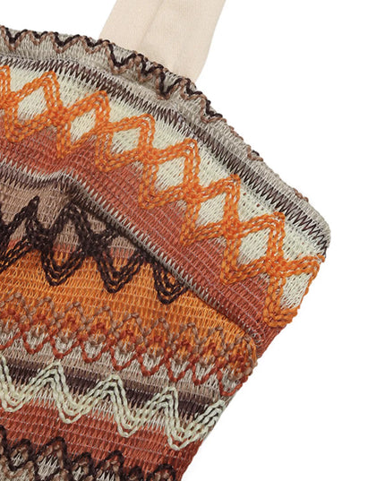 Knit tie shoulder jumpsuit close-up with orange, brown, and cream zigzag pattern. Smocked and tied details visible.