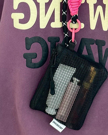 Black mesh coin purse makeup bag with pink lanyard and keychain holding cosmetics and cards