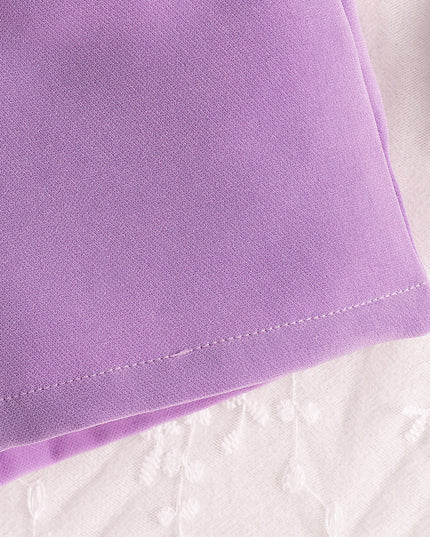 Close-up of lavender fabric with stitching, part of a children's crop top and shorts set.