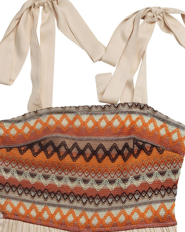 Tie shoulder jumpsuit with a smocked bodice featuring a geometric earth-tone print in orange, brown, and cream.